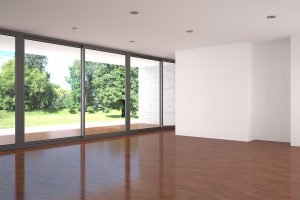 Empty modern living room with large window and parquet floor.